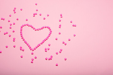 Heart-shaped frame made with small hearts on a pink background.