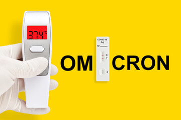 Rapid antigen test kit with positive result. Thermometer in hand isolated on a yellow background....