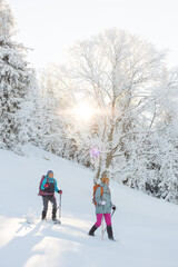two girls in snowshoes walk in the snow. hiking in the mountains in winter.