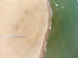 aerial view of beach landscape with loungers and pink umbrellas close to sea.