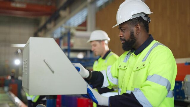 Male engineer is programming a CNC milling machine at modern factory. Industrial plant engineers plan machine maintenance.