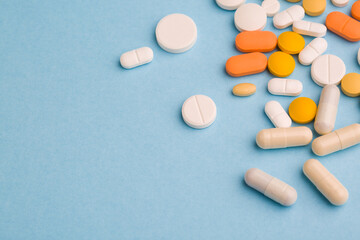 Assorted pharmaceutical medicine pills, tablets and capsules on blue background. Copy space for text