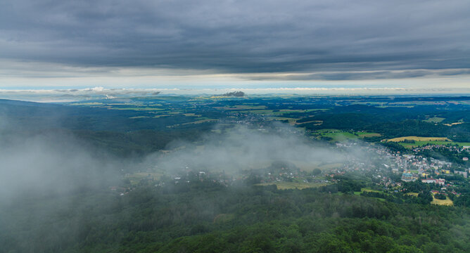view from hill to valley with rolling clouds over small town