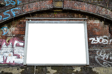 Blank billboard on dark red brick wall with graffiti in urban environment