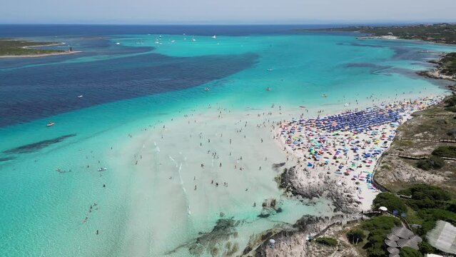 People swim and relax at crowded La Pelosa beach in Sardinia, Italy - 4k Aerial Circling