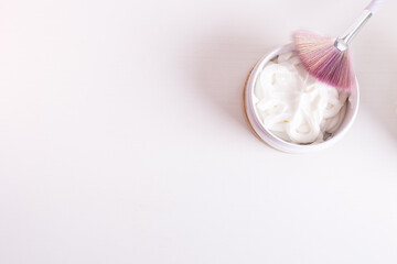 top view of cream facial mask with flat wide brush to apply it