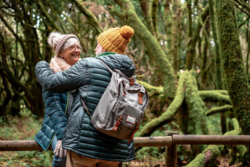 Lovely senior couple enjoying nature outdoors in a mountain forest with moss covered trunks. Joyful elderly couple traveling together in Garajonay national park of La Gomera