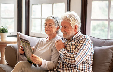 Smiling senior couple sitting together on the couch watching a brochure of the Garajonay de La...