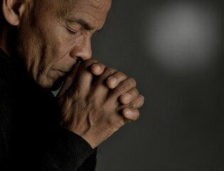 man praying to god at home on black background with people stock photo