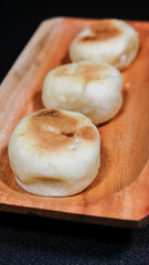 Bakpia Jogja, Bakpia Pathok is a typical Yogyakarta food made from a mixture of green beans, which is wrapped in flour, then baked. Selective focus. Served in wooden plate. Isolated Black Background.