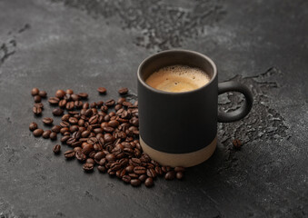Coffee beans with cup of hot creamy black coffee on black background.