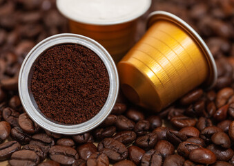 Capsules with ground coffee on fresh raw aroma beans.