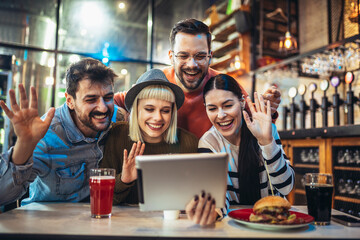 Young friends looking at digital tablet while sitting in cafe.