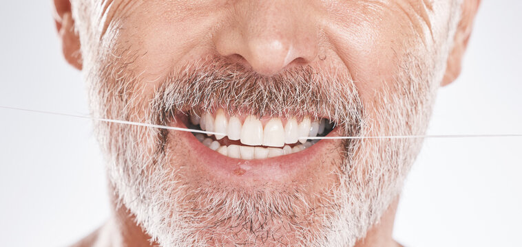 Dental, floss and mouth of senior man in studio isolated on a gray background. Hygiene, cleaning and elderly male model with product flossing teeth for oral wellness, tooth care and healthy gums.