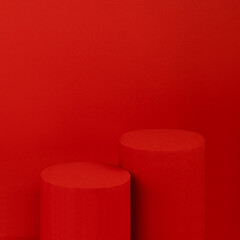 Festive elegant saturated red stage with two cylinder podiums for presentation cosmetic products, gifts, goods in luxury modern style, copy space, square. Template for advertising, design, card.