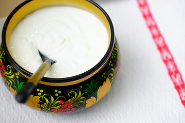 Russian folk Khokhloma dishes with sour cream on the napkin with Slavic pattern.