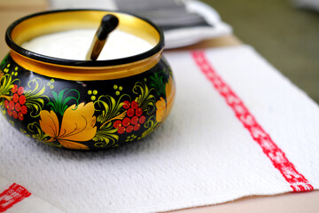 Russian folk Khokhloma dishes with sour cream on the napkin with Slavic pattern.