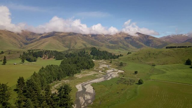 Winding river coming from the mountains flowing through a wide river bed. Aerial dolly-in