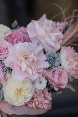 Beautiful spring flowers in box on woman hands. Preserved arrangement in grey round box. Women's day.