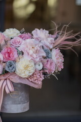 Beautiful spring flowers in box on woman hands. Preserved arrangement in grey round box. Women's day.