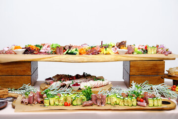 Buffet table with cold appetizers. Meat and vegetable snacks are placed on wooden stands