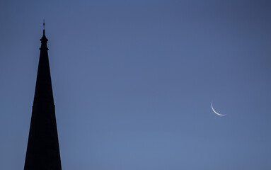 new moon in sunset with church tower 