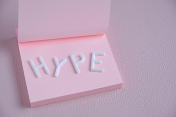 Word hype laid out white letters pink piece paper.Concept hype, popularity and fun.