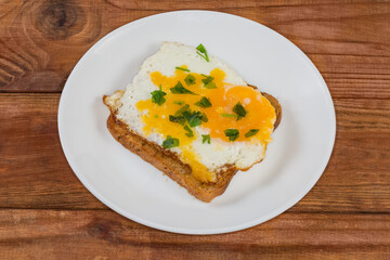 Open sandwich with fried egg on a white dish