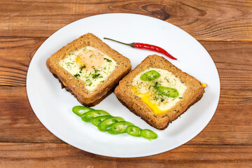 Two open sandwiches with fried egg on a white dish