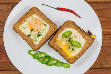 Two open sandwiches with fried egg on a white dish