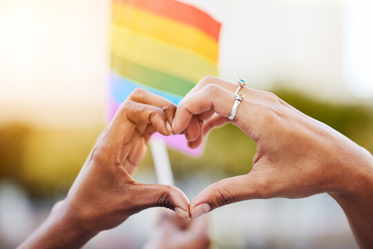 LGBTQ, pride flag and hands with a heart sign for love, equality and solidarity of a gay couple. Rainbow, freedom and closeup of lesbian women with a hand symbol at a gay pride celebration festival.