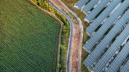 Fly over Solar cells farm beside nature green farm around large industrial factory area. Solar farms are generating renewable energy for the industry.