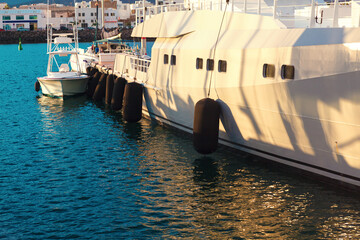 Luxury yacht in the port , side view . Ship fenders on board