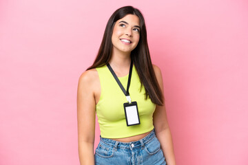 Young Brazilian woman with ID card isolated on pink background thinking an idea while looking up