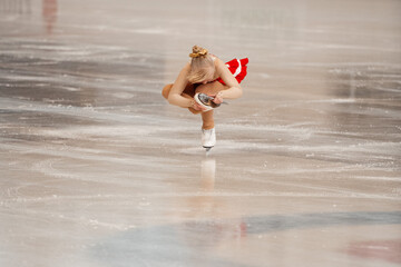 a little girl in a red dress participates in a figure skating competition	