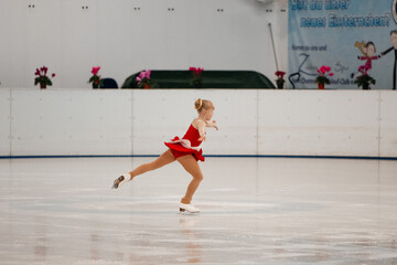 a little girl in a red dress participates in a figure skating competition	