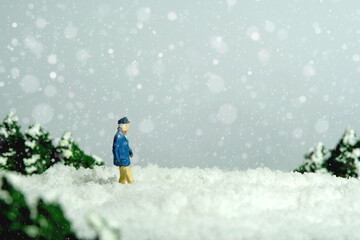 Miniature people toy figure photography. Mobility problem during winter. An old man walking in a...