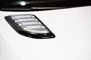 detail of sport car with white metal hood and grey air flow intake ornament