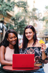 Lesbian couple using a card to buy online sitting outdoors