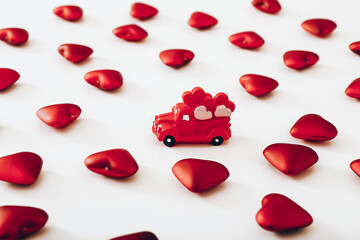 Miniature red car and many hearts on white background. Valentine Day concept