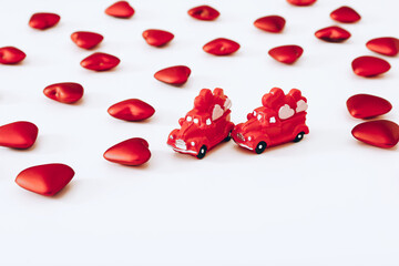 Miniature red cars and red hearts on white background. Valentine Day concept
