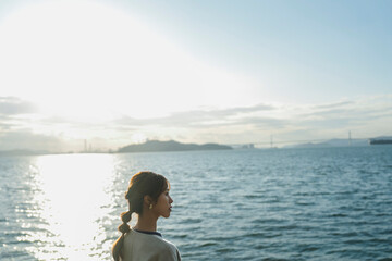 冬の海で夕日を見ている女性