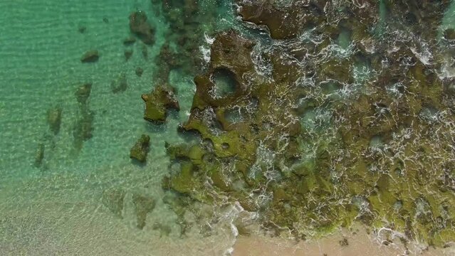 Descending aerial over famous Heart Rock in shallows of Amami Beach, Japan