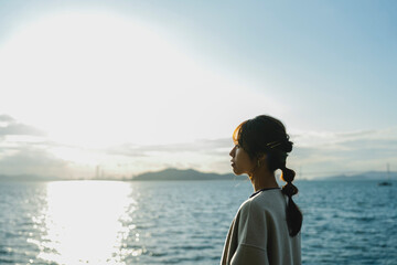 Fototapeta premium 海で夕日を見ている女性