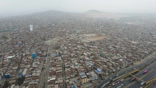 Aerial shot of houses next to a highway in the crowded neighborhood of Ventanilla. Poor slum in Lima Peru