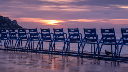 Chaises bleues de la Promenade des Anglais face à la Baie des Anges à Nice en hiver à l'aube