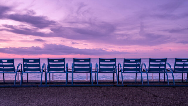Chaises bleues de la Promenade des Anglais face &agrave; la Baie des Anges &agrave; Nice en hiver &agrave; l'aube