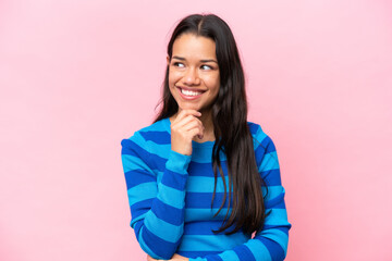 Fototapeta premium Young Colombian woman isolated on pink background thinking an idea while looking up