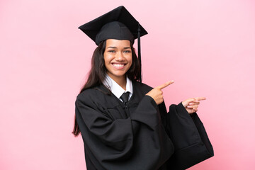 Young university Colombian woman graduate isolated on pink background pointing finger to the side...