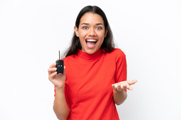 Young Colombian woman holding car keys isolated on white background with shocked facial expression